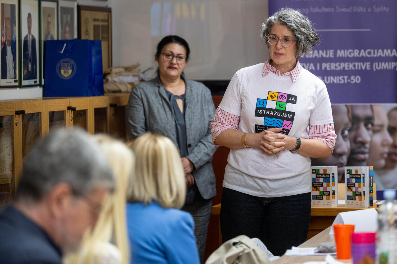 A project member wearing a European Researchers’ Night T-shirt presents her research in front of the UMIP banner.