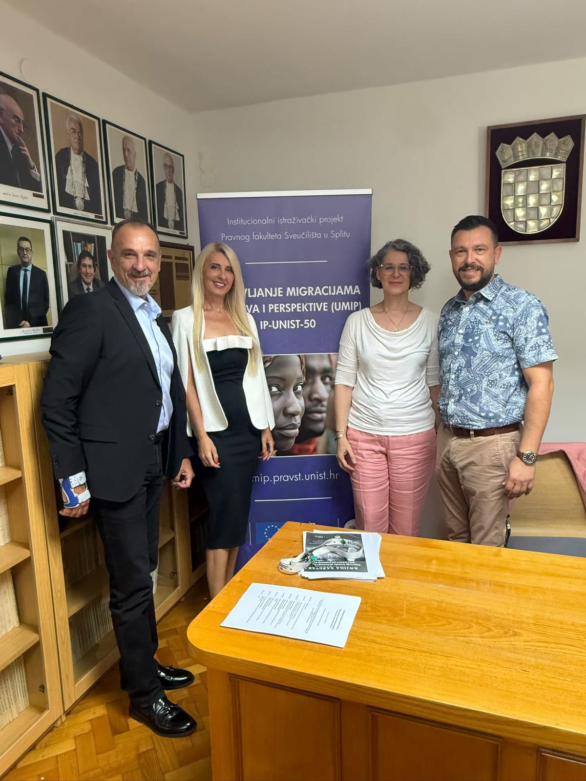 Four participants of the round table in front of the UMIP project banner.