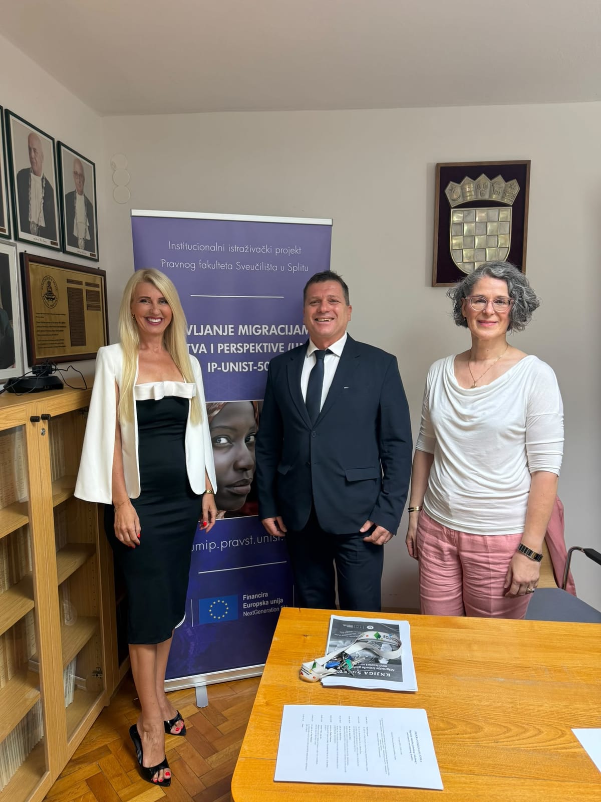 Three participants of the round table in front of the UMIP project banner.